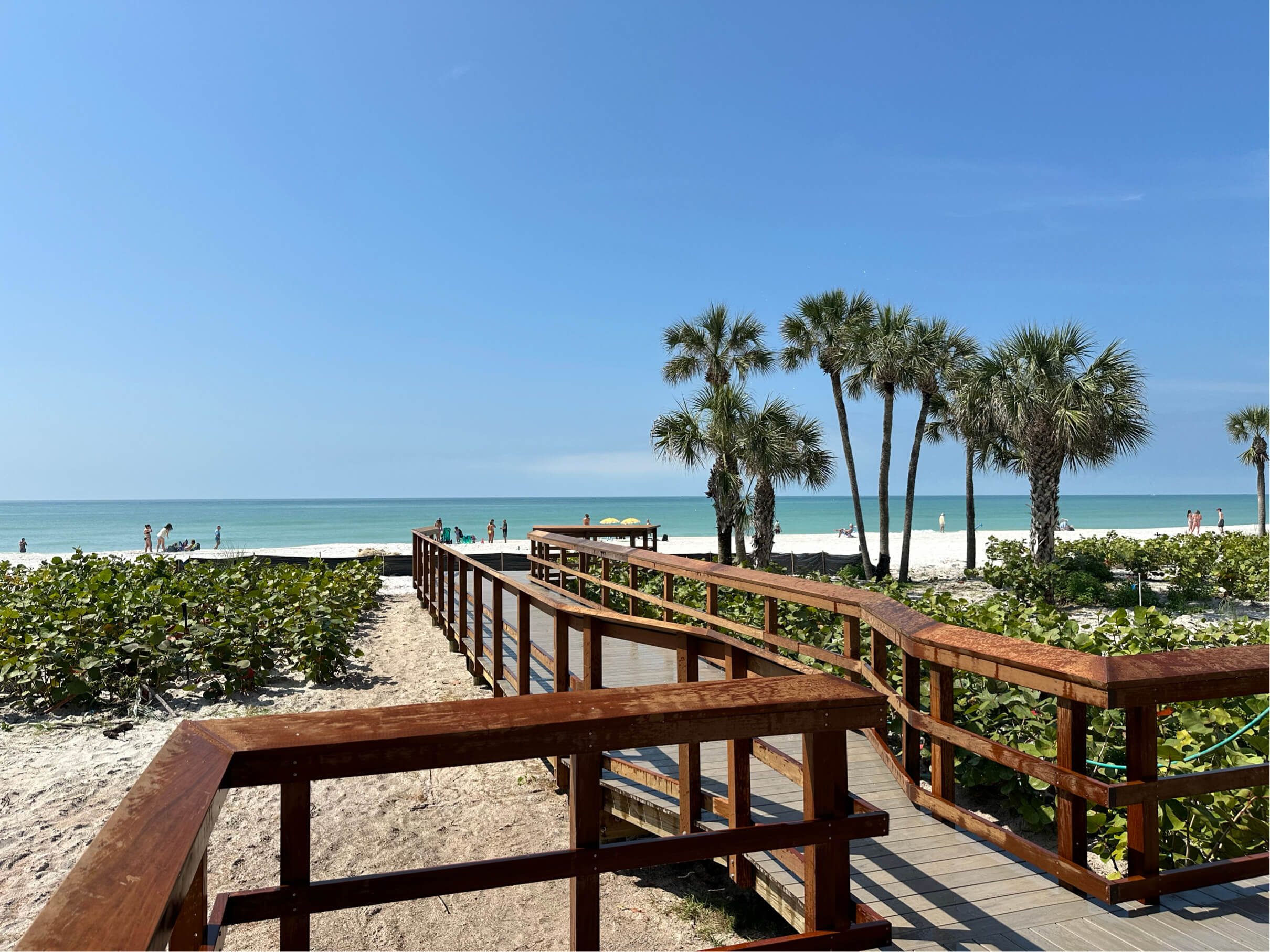 Beach access boardwalk with wooden railing leading to shoreline.