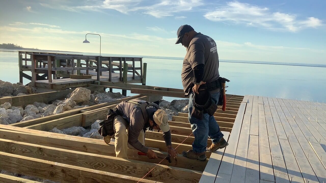 Workers building a waterfront dock frame over the water