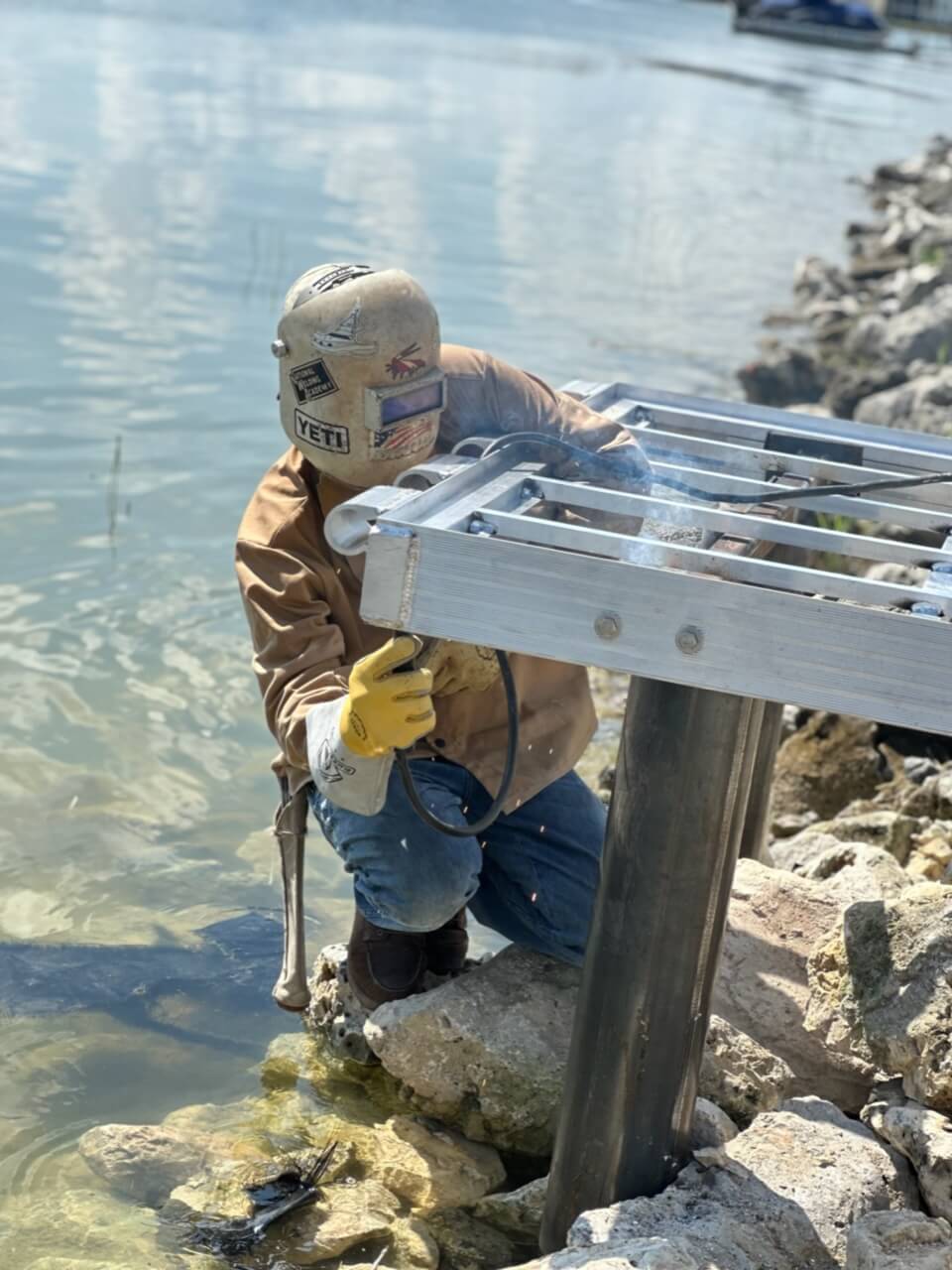 Worker welding and installing metal components for a waterfront dock